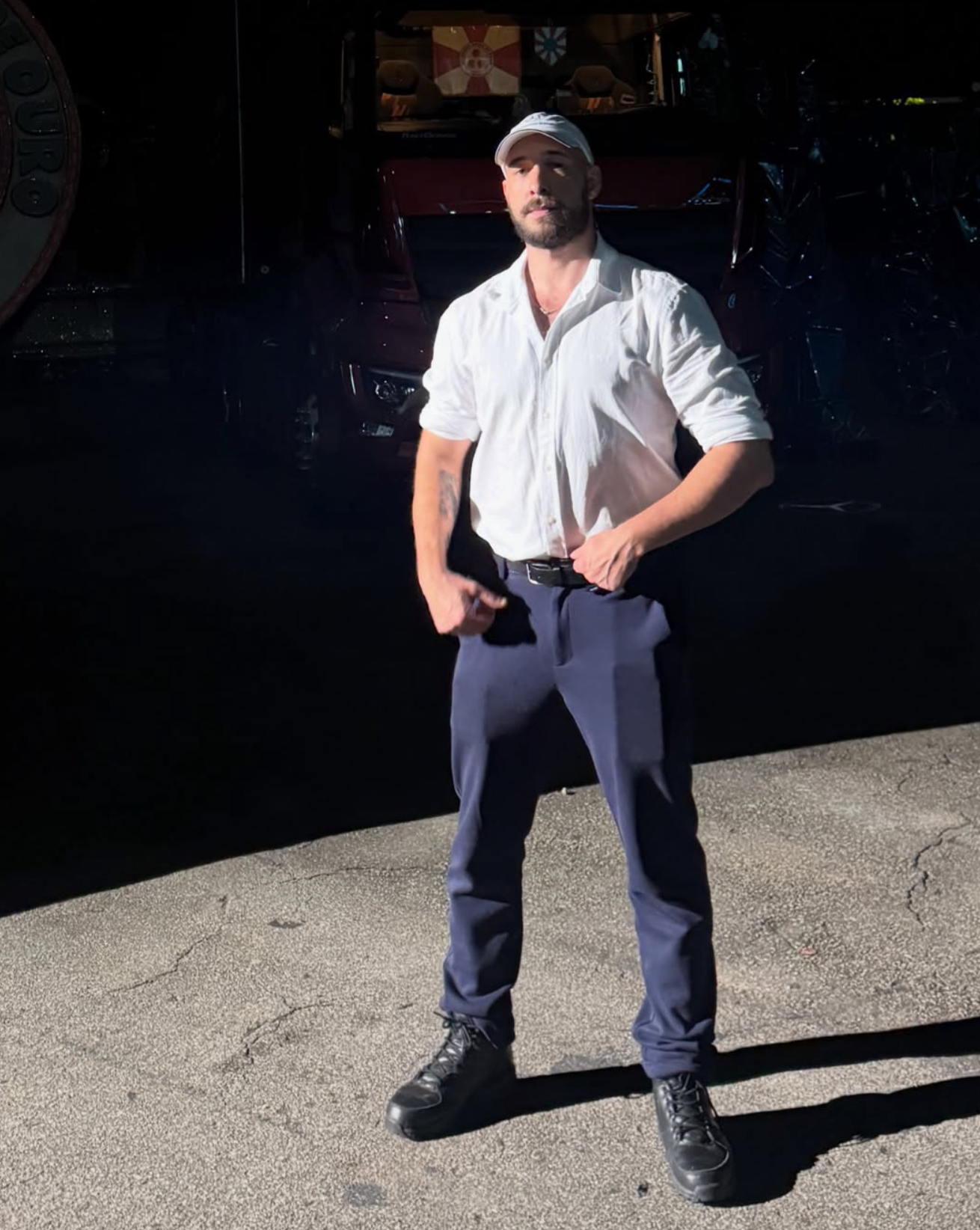 Rodolfo Goulart com camisa branca, boné branco e calça azul